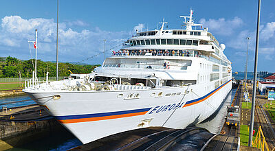 Die Europa nimmt 2028 Kurs auf den Panama-Kanal mit Ziel Kolumbien, Costa Rica und Panama Kreuzfahrtschiff MS Europa von Hapag-Lloyd in einer Schleuse des Panamakanals, umgeben von tropischer Vegetation.