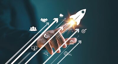 Welche Unterstützung benötigen Menschen der Generationen Z und Y, um ein Unternehmen zu gründen? Das wollen Centouris und Reiseland herausfinden Im Vordergrund ist eine Hand zu sehen, die eine aufsteigende Rakete und Pfeile mit Geschäftssymbolen wie Zielscheibe, Netzwerk und Wachstum auslöst. Das Bild steht für Fortschritt, Start-up-Erfolg und Online-Business-Strategien.