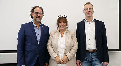 Wollen den VUSR als Branchenverband etablieren: Der VUSR-Vorstand mit Chefin Marija Linnhoff, Cyrus Nurischad (links) und André Röckmann. Foto: rie Zwei Männer und eine Frau im mittleren Alter stehen lächelnd in legerer Business-Kleidung vor einer beigen Wand