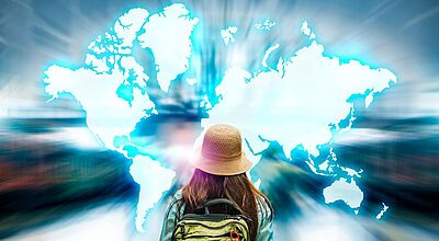 Wohin geht die Reise? Auf der Reiseplattform Mindtrip liefert die KI Inspiration – und TUI die passenden Angebote. Foto: Chan2545/iStock Eine Person mit Rucksack und Hut blickt auf eine leuchtend blaue Weltkarte, die sich vor ihr ausbreitet – Symbol für globale Reisemöglichkeiten und digitale Reiseinspiration.